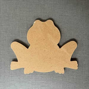 May include: A brown wooden cutout of a frog, with a simple design. The frog is sitting on a branch.