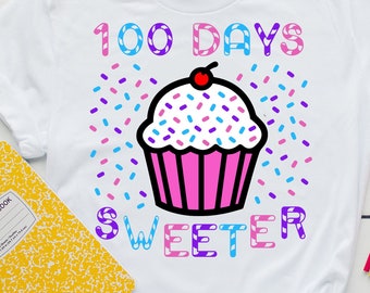 May include: White t-shirt with a pink cupcake graphic and the text "100 Days Sweeter" in rainbow colors. The cupcake has a red cherry on top and is surrounded by colorful sprinkles.