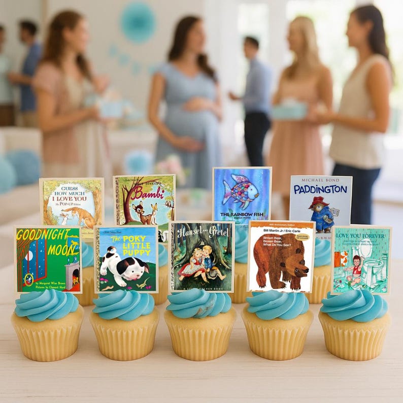 K&ouml;nnte beinhalten: Cupcakes mit blauer Glasur, gekr&ouml;nt von Miniatur-Buchcovern. Zu den B&uuml;chern geh&ouml;ren Titel wie "Goodnight Moon", "Bambi" und "Paddington". Die Cupcakes sind auf einer hellen Oberfl&auml;che angeordnet, wahrscheinlich f&uuml;r eine Babyparty.