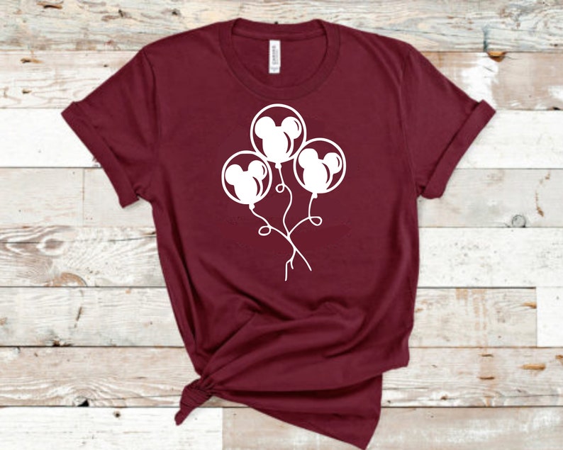 May include: A maroon t-shirt with a white graphic of three Mickey Mouse head balloons.