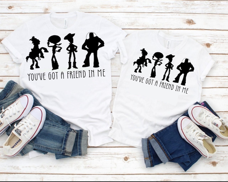 Pu&ograve; includere: Due magliette bianche con una silhouette nera dei personaggi di Toy Story, Woody, Buzz Lightyear, Jessie e Bullseye. Il testo "You've got a friend in me" &egrave; stampato sotto i personaggi.