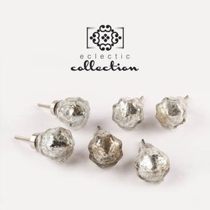 May include: Six silver glass cabinet knobs with a textured, aged finish. The knobs are in various shapes and sizes. The text "eclectic collection" is displayed above the knobs.