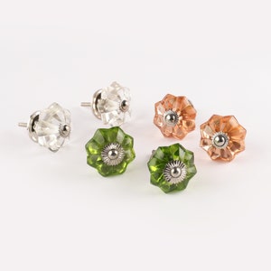 May include: Five glass cabinet knobs with a flower design. Two are clear, one is peach, and two are green.