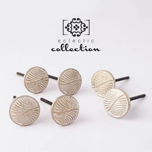 May include: Six white ceramic drawer knobs with a wavy pattern and black metal screws. The knobs are arranged in a semi-circle on a white surface. The text "eclectic collection" is visible above the knobs.