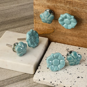 May include: Five blue ceramic flower-shaped cabinet knobs with silver hardware.