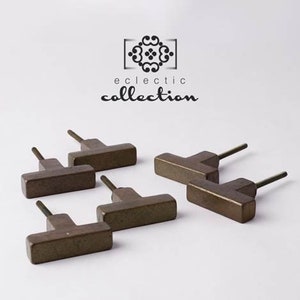 May include: Six antique bronze cabinet knobs with a T-shaped design. The knobs have a rustic, aged finish.