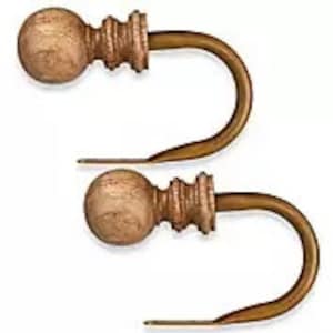 May include: Two wooden curtain tiebacks with a round knob and a gold metal hook. The tiebacks are a light brown color.
