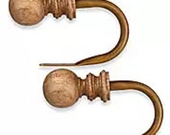 May include: Two wooden curtain tiebacks with a round knob and a gold metal hook. The tiebacks are a light brown color.