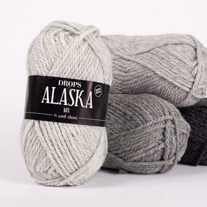 May include: Three skeins of Drops Alaska yarn in shades of gray. The label reads "Drops Alaska Mix 100% Wool A wool classic."