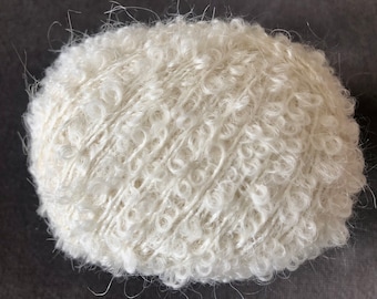 May include: A ball of white yarn with a fuzzy texture. The yarn is wound into a ball shape and is ready for knitting or crocheting.