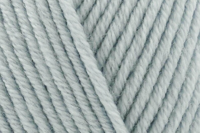 May include: A close-up view of light blue yarn featuring a multi-ply twisted construction. The fibers show a soft, slightly fuzzy texture with consistent diagonal alignment across the frame, highlighting the individual strands of the spun thread.