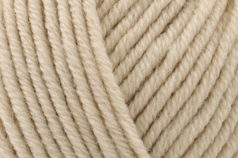 May include: A close-up view of a ball of yarn featuring a light beige, neutral color. The texture consists of multiple strands of twisted fiber arranged in parallel lines, creating a consistent, repeating pattern across the entire surface area.