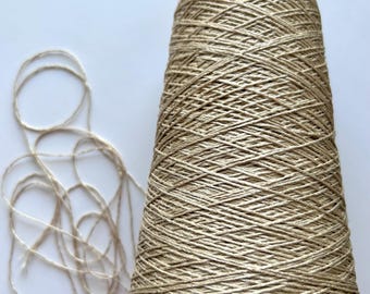 May include: A spool of natural beige linen yarn with a small amount of yarn unwound.