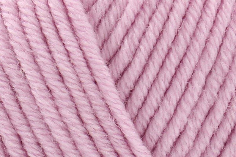 May include: A close-up view of light pink yarn featuring a multi-ply twisted construction. The fibers are arranged in parallel diagonal lines, showcasing the texture and soft pastel color of the spun thread in a detailed, high-resolution format.