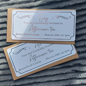 May include: Two white cards with black and silver lettering announce an afternoon tea event at Waterford Castle on March 10th at 1 pm. One card is addressed to Eily.