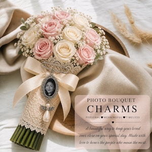 Op de afbeelding: Een boeket van roze en crèmerozen met gipskruid, verpakt in kant en lint. Een fotobedel met een engelenhanger is bevestigd. De tekst op de afbeelding luidt: "PHOTO BOUQUET CHARMS PERSONAL MEANINGFUL TIMELESS".