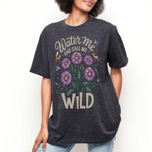 May include: A dark gray t-shirt with a floral design and the text "Water Me and Call Me Wild".
