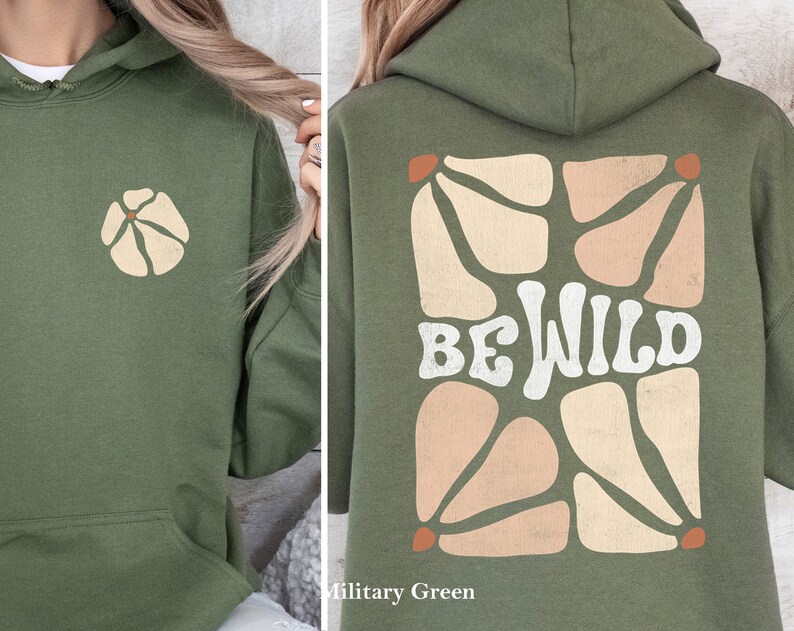 Op de afbeelding: Een groene hoodie met een witte "Be Wild" afbeelding op de rug en een klein bloemetjesontwerp op de voorkant. De hoodie is gemaakt van een zacht, comfortabel materiaal en heeft een ontspannen pasvorm.