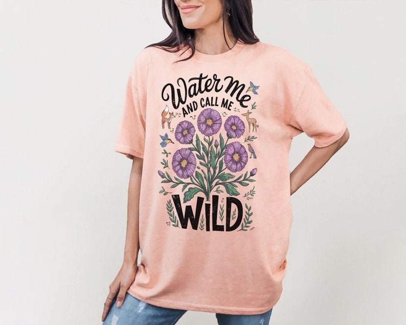 May include: A light pink t-shirt with a floral design and the text "Water me and call me wild".