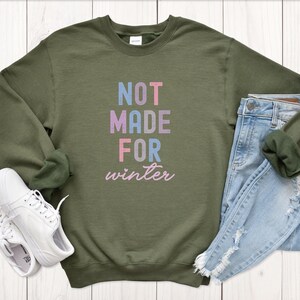 May include: A green sweatshirt with the text "NOT MADE FOR winter" in colorful letters.