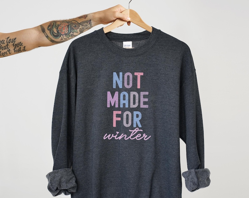 May include: A dark gray sweatshirt with the text "NOT MADE FOR winter" in a rainbow color scheme.