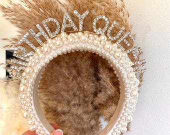 Puede incluir: Una diadema blanca con adornos de perlas y una tiara dorada de "Birthday Queen".