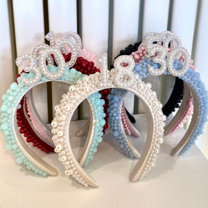 May include: Five pearl-embellished headbands with different coloured beads and silver numbers. The numbers are 30, 18, 30, 18, and 30.