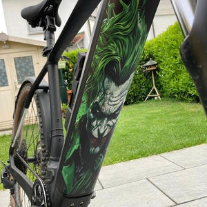 Op de afbeelding: Een zwarte elektrische fiets met een groene en witte Joker-afbeelding op het frame.