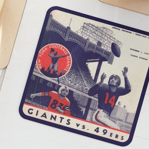 May include: A vintage-style coaster featuring a blue and white illustration of a football game between the New York Giants and the 49ers. The text "Giants vs. 49ers" is printed in blue at the bottom of the coaster.