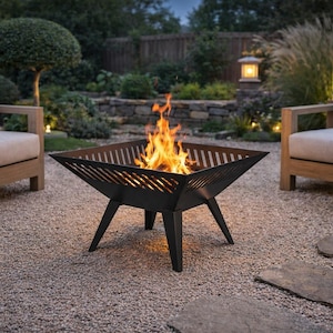 May include: A black, square fire pit with a burning fire, set on a gravel patio. The fire pit has a geometric design and is supported by angled legs. Two wooden outdoor sofas with cushions are in the background.