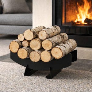 Puede incluir: Un soporte de metal negro para leña lleno de troncos de abedul. Los troncos están apilados ordenadamente, listos para una chimenea. La chimenea está al fondo, con llamas visibles. La habitación tiene una combinación de colores neutros.