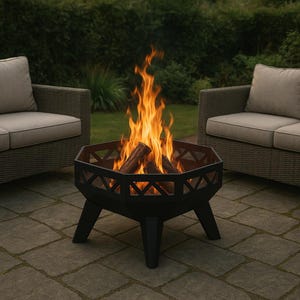 May include: A black, geometric fire pit with burning logs. The fire pit has a decorative cut-out design and sits on three legs. The flames are bright orange and yellow. Two wicker chairs with beige cushions are in the background.