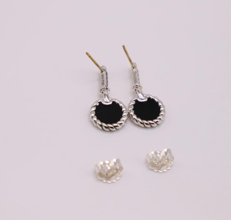 Puede incluir: Un par de pendientes de plata con piedras de &oacute;nix negro y un dise&ntilde;o de cuerda trenzada. Los pendientes son de estilo colgante y tienen un cierre de poste.