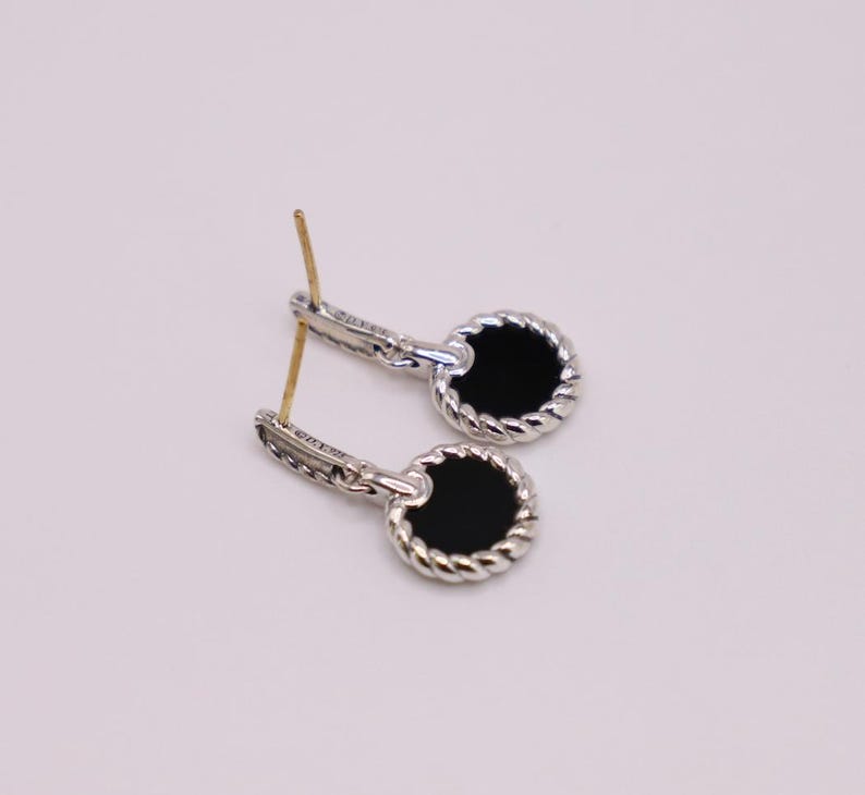 Puede incluir: Un par de pendientes de plata con piedras de &oacute;nix negro. Las piedras est&aacute;n engastadas en un dise&ntilde;o de cuerda.