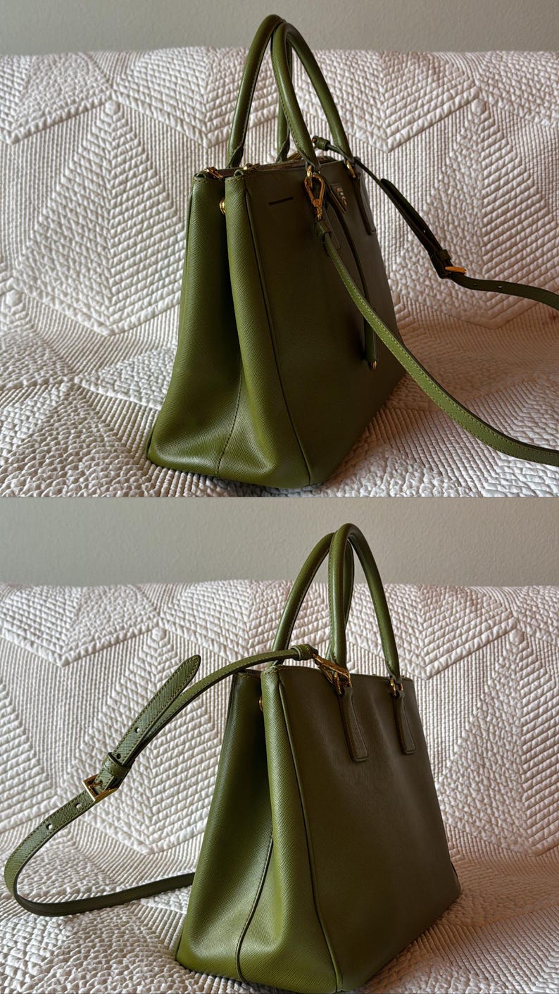 May include: Olive green handbag with top handles and a detachable shoulder strap. The bag features gold-tone hardware and a structured design. The bag is made of a smooth material and has a rectangular shape.