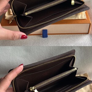 May include: A brown leather zippered wallet with gold hardware. The wallet is open and the inside is lined with brown fabric.