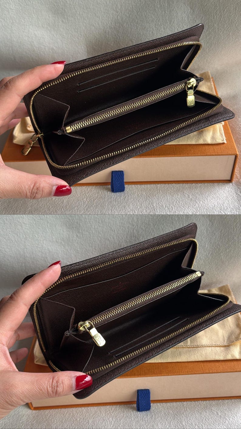 May include: A brown leather zippered wallet with gold hardware. The wallet is open and the inside is lined with brown fabric.