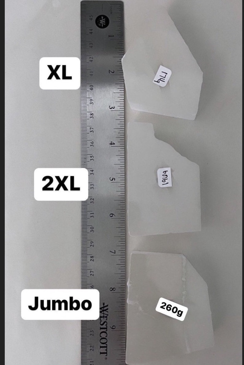 Peut inclure: Trois cristaux de s&eacute;l&eacute;nite blancs de diff&eacute;rentes tailles &eacute;tiquet&eacute;s XL, 2XL et Jumbo. Les cristaux sont &agrave; c&ocirc;t&eacute; d'une r&egrave;gle avec des mesures en pouces. Les cristaux sont &eacute;tiquet&eacute;s avec leur poids en grammes : 174 g, 190 g et 260 g.