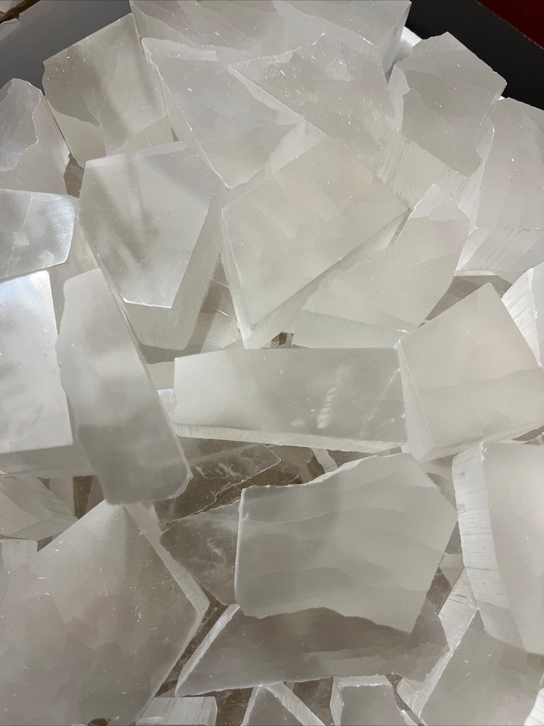 Peut inclure: Un tas de morceaux de cristal de s&eacute;l&eacute;nite blanche. Les cristaux sont translucides et ont une surface lisse et polie.