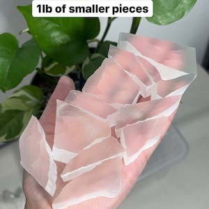 Peut inclure: Une main tenant un tas de petits morceaux de cristal de s&eacute;l&eacute;nite rose translucide. Le texte "1lb of smaller pieces" est visible sur l'image.