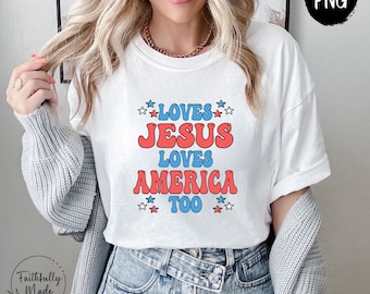 Op de afbeelding: Wit T-shirt met rode en blauwe tekst die "Loves Jesus Loves America Too" luidt met sterren rond de tekst.