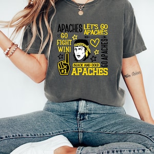 May include: Dark gray t-shirt with the text "APACHES" in yellow and white, along with a graphic of a Native American figure and a foam finger. The shirt also features the phrases "Let's Go", "Fight Win!", and "Black and Gold".