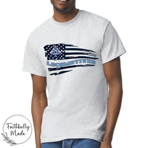Può includere: Una maglietta grigia con un design a bandiera americana rovinato che presenta un logo di locomotiva blu e bianco e il testo "LOCOMOTIVES".