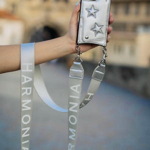 Funda para teléfono y billetera con diseño cruzado Harmonia Ny Stars en color plateado, compatible con iPhone 15 Pro Max