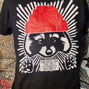 De rijken zijn de enige gevaarlijke minderheid, met een wasbeer-T-shirt