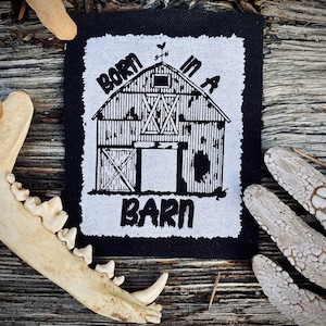 May include: Black and white embroidered patch featuring a barn illustration and the text "Born in a Barn".