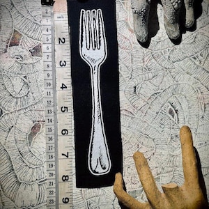 May include: A black fabric patch with a white outline of a fork. The patch is approximately 5 inches tall and 2 inches wide.