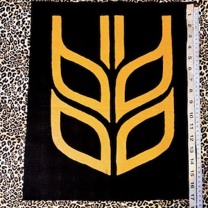 May include: A black canvas featuring a golden wheat-like design. The artwork measures approximately 40 cm tall and 30 cm wide. The background is a leopard print fabric.