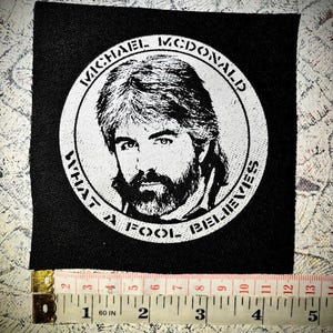 May include: Black and white embroidered patch with a portrait of Michael McDonald and the text "What a Fool Believes".