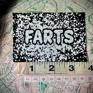 Het is een patch met de tekst Farts!  naai er een aan je kont.